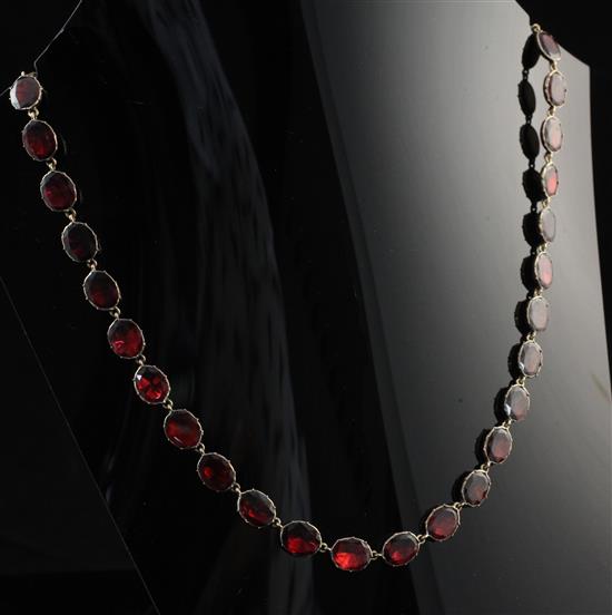 An Edwardian 9ct gold and garnet riviere necklace, 16.5in.